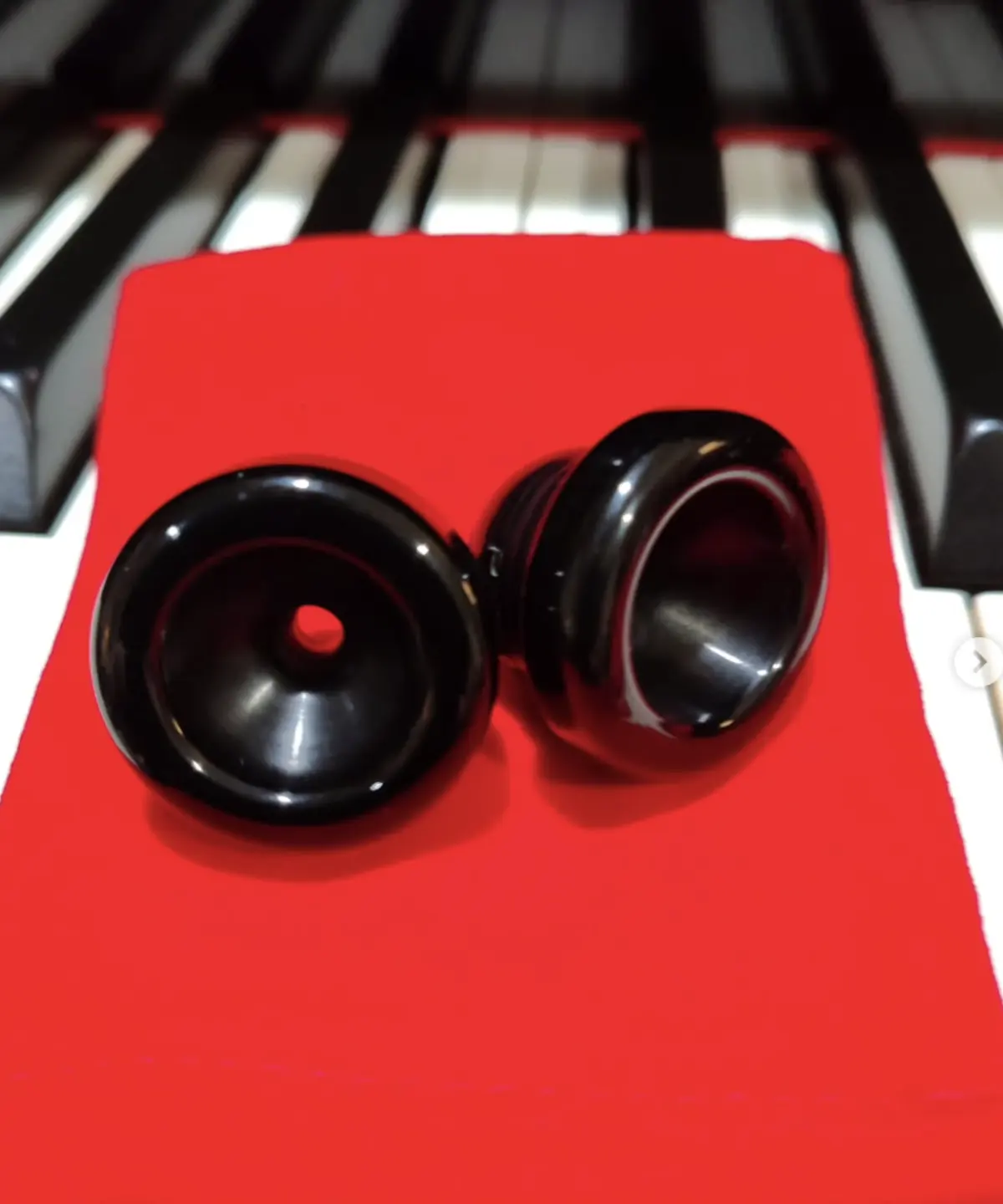 Black Phoenix Brass mouthpiece cups displayed on a red pouch across piano keys