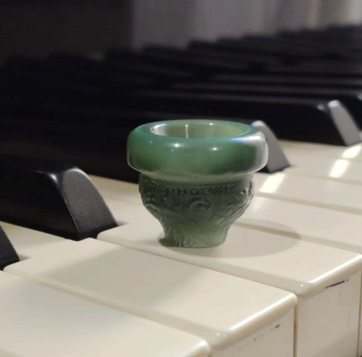 Close-up of a green Phoenix Brass mouthpiece showing its polished rim and sculpted body